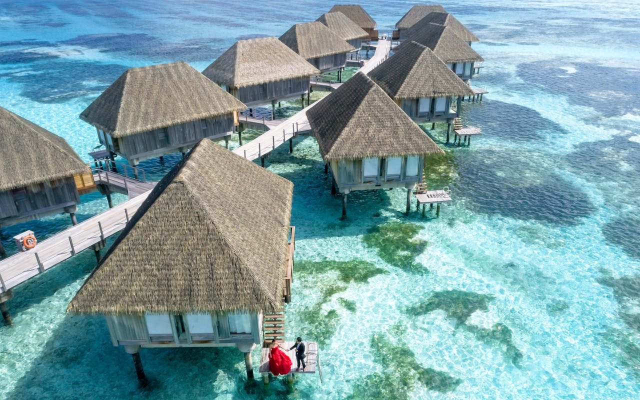 our-story Stunning aerial view of overwater bungalows in Fuvahmulah, Maldives, with crystal clear waters.