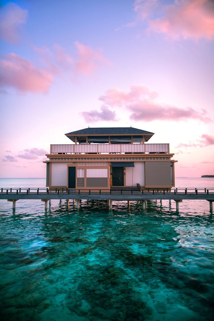 services-02 Stunning overwater villa at sunset in the Maldives with vibrant skies and turquoise waters.