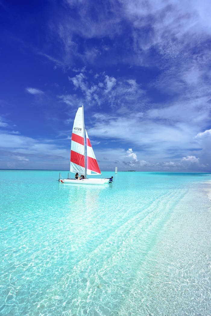 services-01 Idyllic scene of a sailboat on pristine turquoise waters under a clear blue sky in the Maldives.
