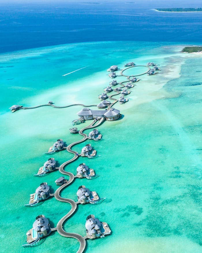 services-03 Aerial view of luxury overwater villas at Noonu Atoll, Maldives with turquoise waters.